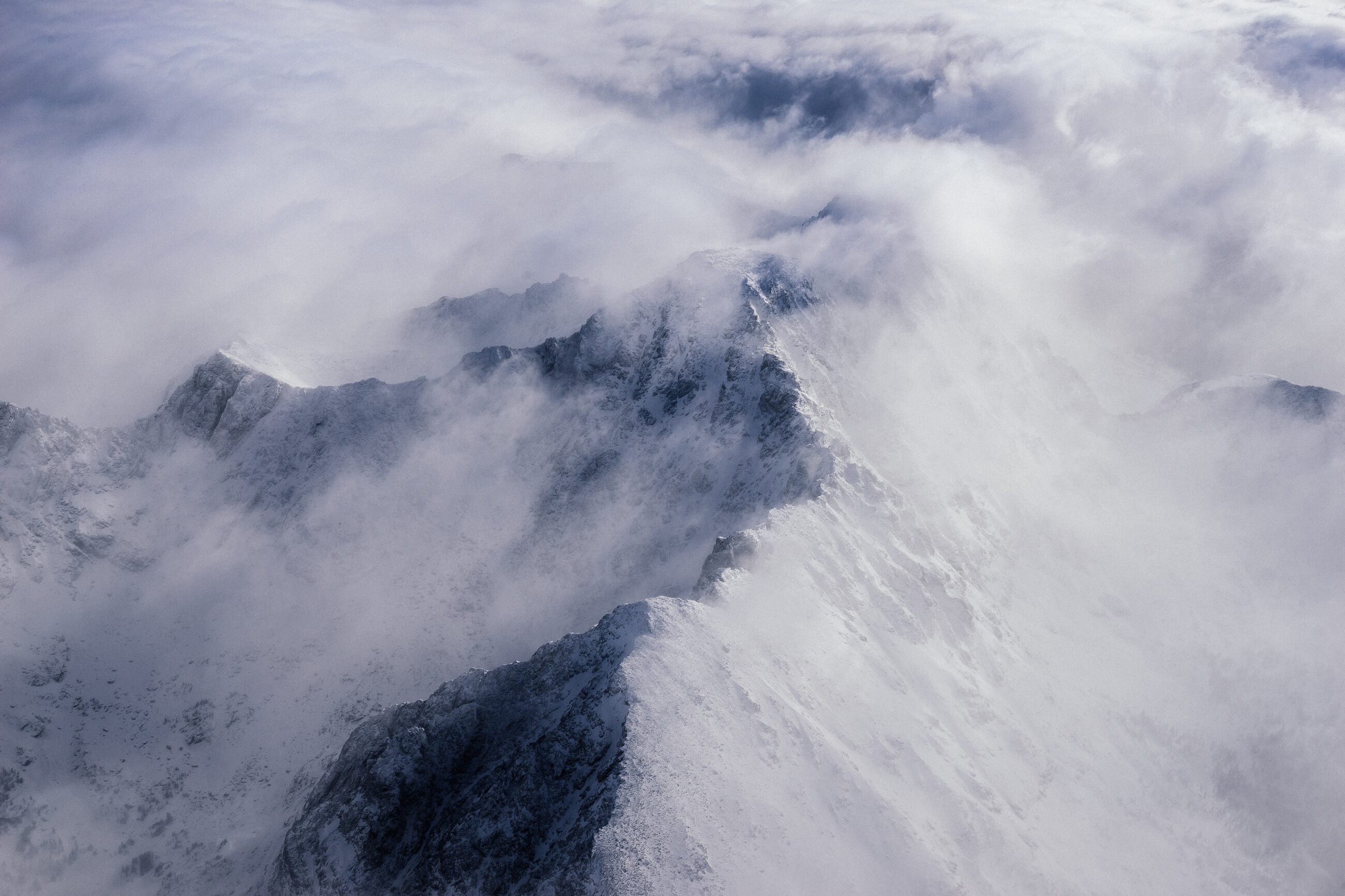Cloud pouring over a snowy ridge in the Front Range